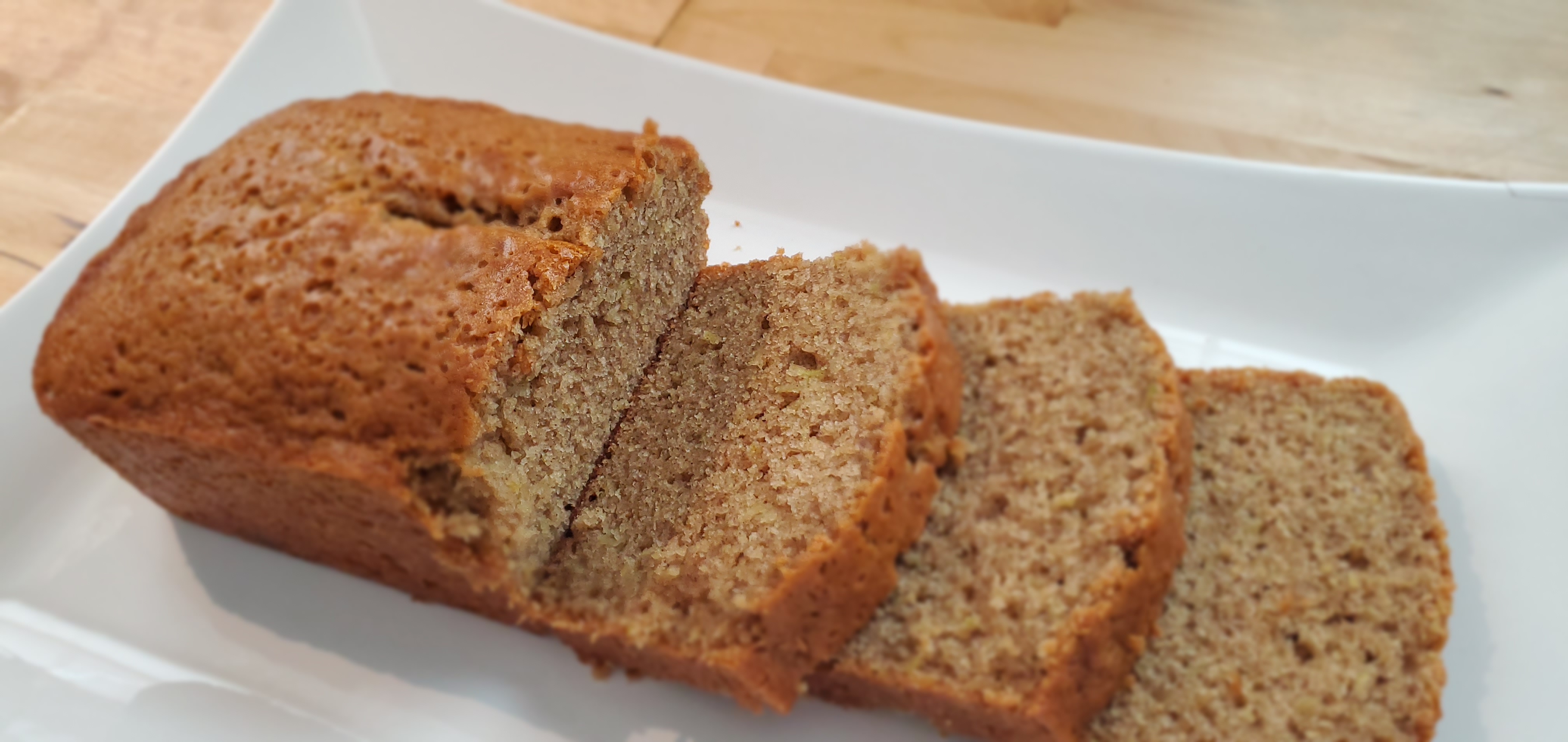 Freshly baked and sliced zucchini bread on a white platter