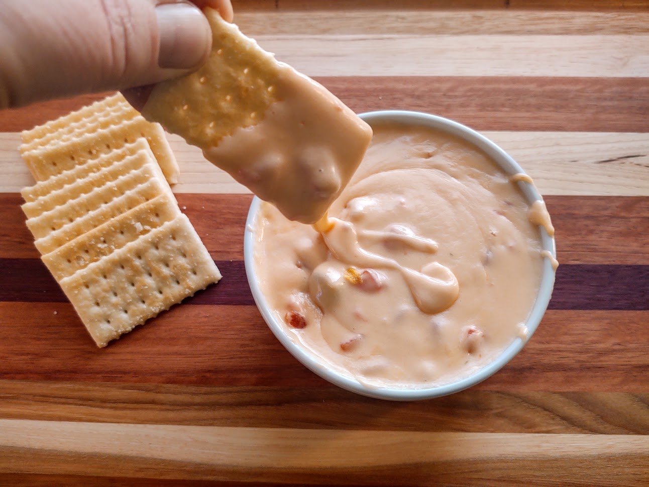 a cracker being dipped into 3 ingredient cheese dip