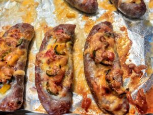 Oven roasted smashed sausages: a sausage split open, filled with onions, jalapeno, bell pepper, and covered with melted cheese