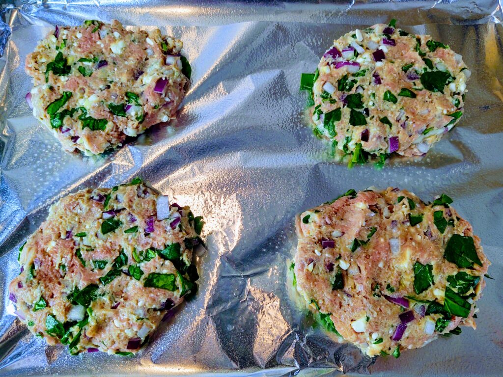 Prepared and ready to bake Mediterranean turkey burgers on a sheet pan.