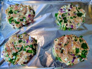 Prepared and ready to bake Mediterranean turkey burgers on a sheet pan.