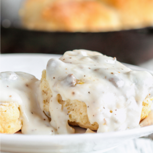 a white plate with biscuits covered in gravy