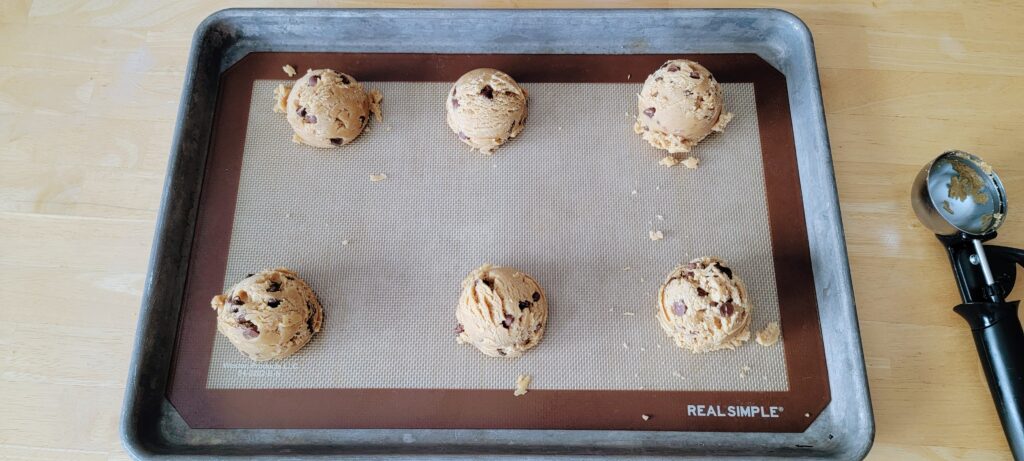 scooped cookie dough on a baking mat and sheet pan.